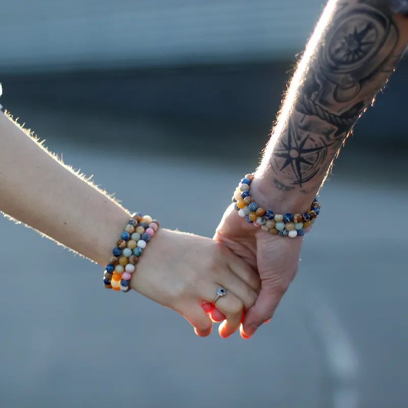 couple amoureux main dans la main avec des bracelets en pierres naturelles porteuses d'énergie positive