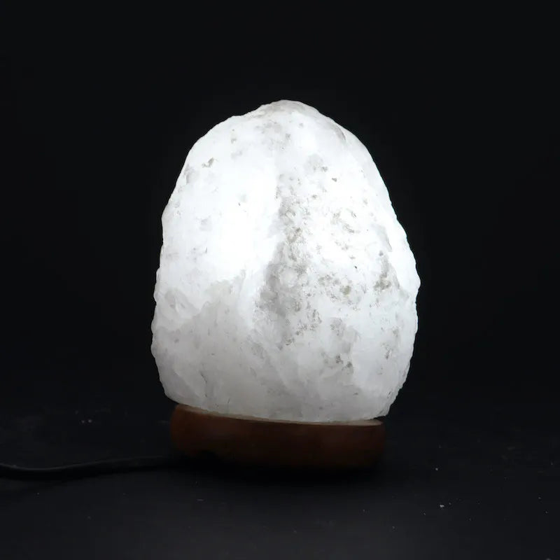 Lampe en cristal de sel de l'Himalaya éclairée, émettant une douce lumière chaude dans l'obscurité. Parfaite pour une ambiance apaisante et relaxante.