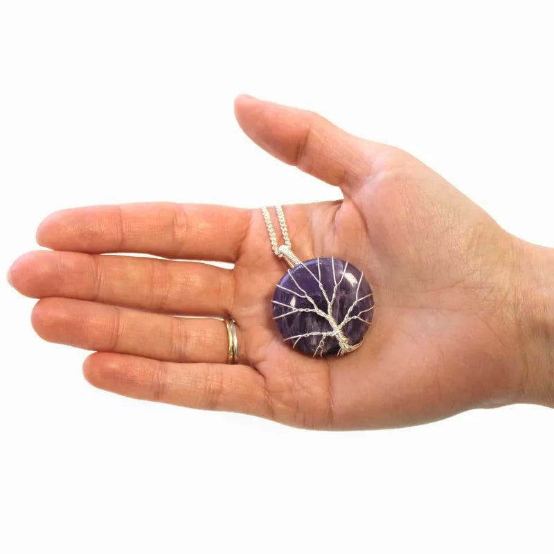 pendentif en pierre polie d'amethyste et fil torsadé en motif d'arbre de vie tenue dans la main